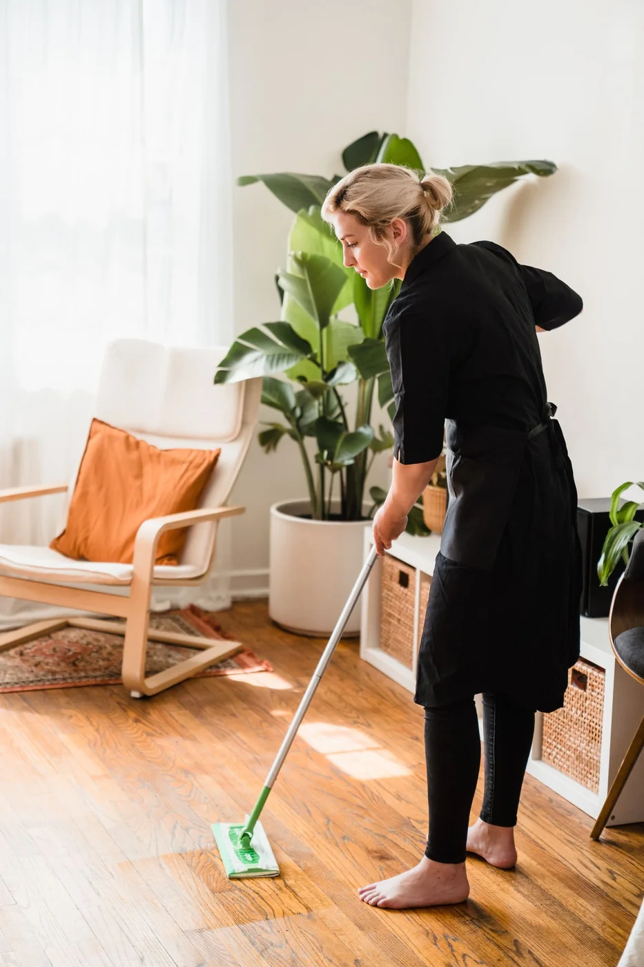 Woman mopping a sunlit home floor.